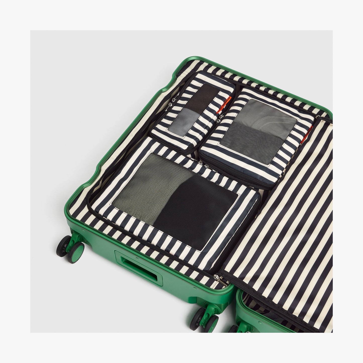 Set of Six / Poplin Stripe Black | Poplin Stripe Black compressible packing cubes neatly organized inside a Jungle Green open suitcase